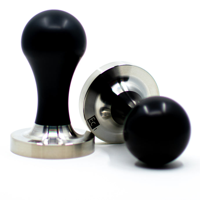 Two EC1 Tampers with black handles and stainless steel pistons; one upright and one on it's side.